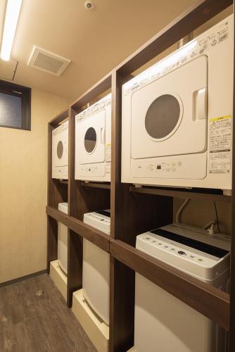 a kitchen with two microwaves and appliances on shelves at hotel H2 TRIP&BUSINESS NAGASAKI in Nagasaki