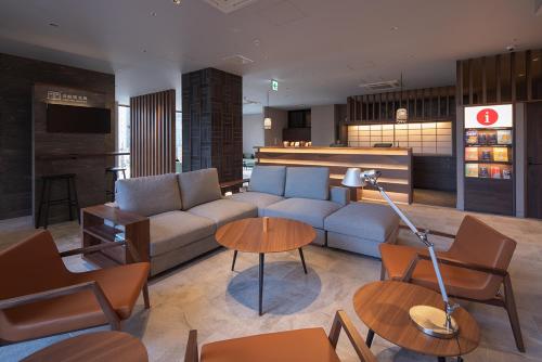 a living room with a couch and tables at hotel H2 TRIP&BUSINESS NAGASAKI in Nagasaki