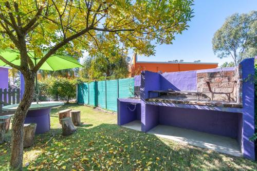 a purple bench next to a tree and a fence at Las Coloniales in Sauce de Portezuelo