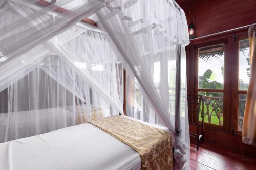 a bed with a canopy in a room with a window at The Hideout Sigiriya in Sigiriya