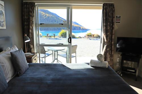 a bedroom with a bed and a view of a beach at Lakes Edge Holiday Park in Lake Tekapo