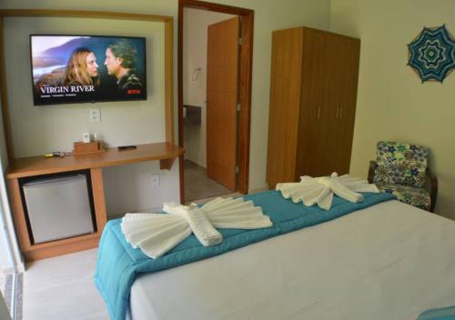 a bedroom with a bed with a tv on the wall at Pousada Cantinho da Praia in Paraty