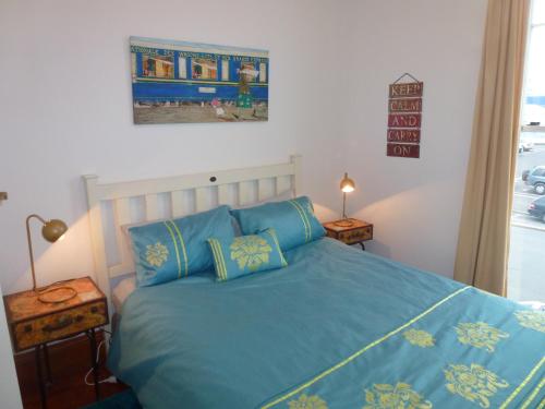 a bedroom with a blue bed with two pillows at Old world charm in town and by the sea in Napier