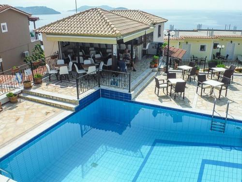 a swimming pool with chairs and tables and a house at Fiorella Sea View in Megali Ammos