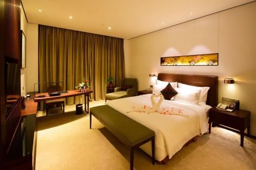 a hotel room with a large bed and a desk at Wuxi Yew Resort in Wuxi
