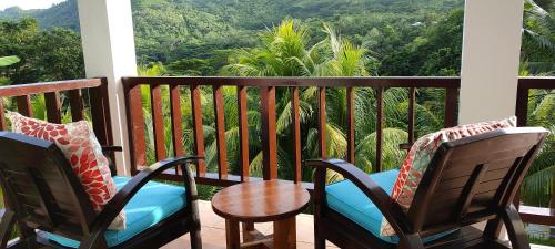 a balcony with two chairs and a table and a view at Chalets Des Vacances in Takamaka