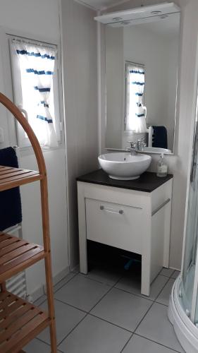 ein weißes Badezimmer mit einem Waschbecken und einem Spiegel in der Unterkunft Villa Moris in Dolus d'Oléron