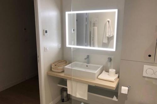 a white bathroom with a sink and a mirror at Elégante maison d'architecte, Spa à débordement in La Noue