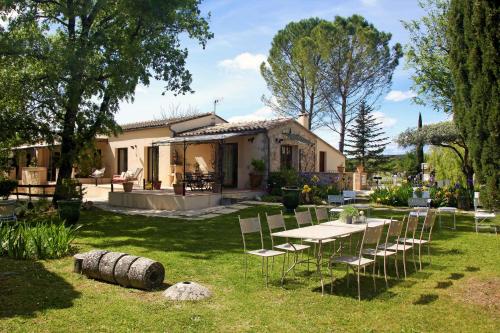 uma mesa e cadeiras em frente a uma casa em La Magnanerie d'Hôtes ,le jardin secret em Sauve
