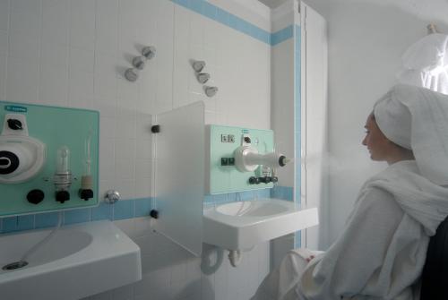 a woman in a bathroom with a sink and a mirror at Hotel Giardino Delle Ninfe E La Fenice in Ischia