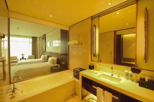 a bathroom with a bath tub and a bedroom at Wuxi Yew Resort in Wuxi