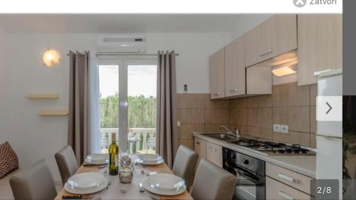 a kitchen with a table and chairs and a kitchen with a table and a counter at Apartments Lolo in Privlaka