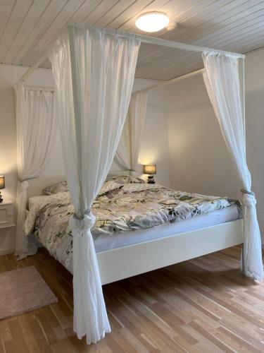 a bedroom with a canopy bed with white curtains at Topagergaard in Bredsten