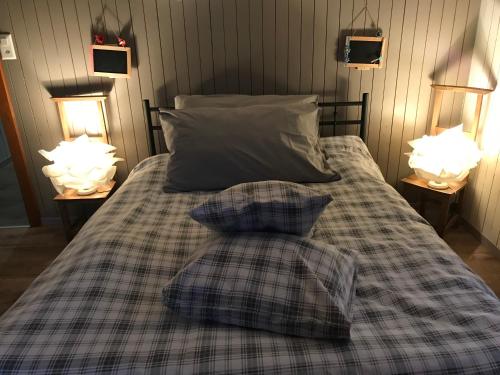 a bed with two pillows on it with two lamps at un ptit chalet in Les Brenets