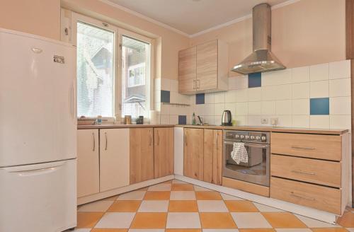 a kitchen with wooden cabinets and a stove at Apartamentai Juodkrantėje in Juodkrantė