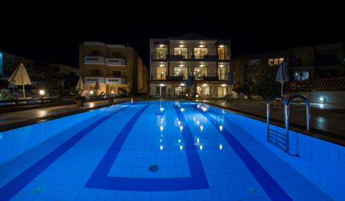 a swimming pool at night with buildings in the background at Giannarakis Beach in Stalos