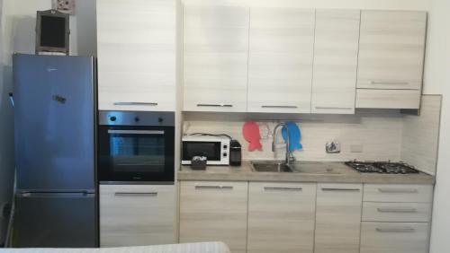 La cuisine est équipée de placards blancs, d'un four micro-ondes et d'un réfrigérateur. dans l'établissement Miriamare, à Albissola Marina