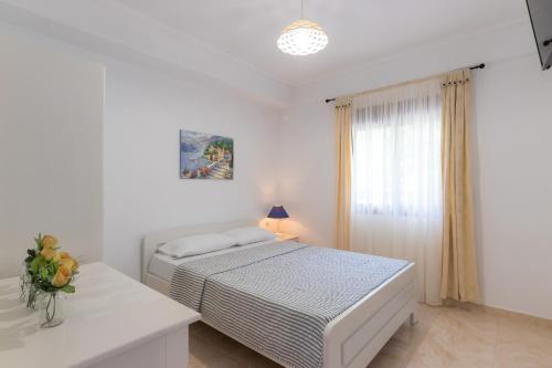 a white bedroom with a bed and a window at Lena Studios in Skala Potamias