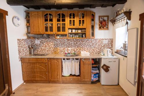 a kitchen with wooden cabinets and a white refrigerator at Ubytovanie na včelej farme in Polichno