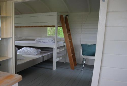 een kamer met 2 stapelbedden en een stoel bij Pipowagen Vlinder bij Pipowagen & Kampeerhoeve s Gravenhof in Netterden