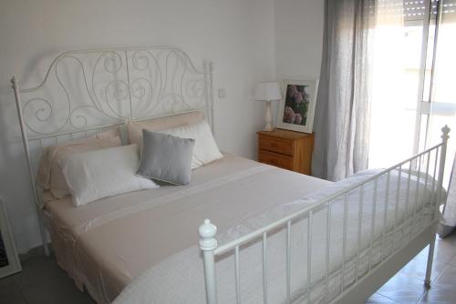 a white bed with a white headboard in a bedroom at Fuzeta beach holiday apartment in Fuzeta
