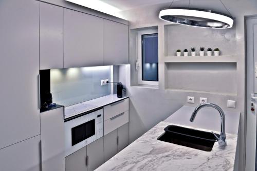 a kitchen with white cabinets and a sink at kolonaki Penthouse panoramic Acropolis view in Athens