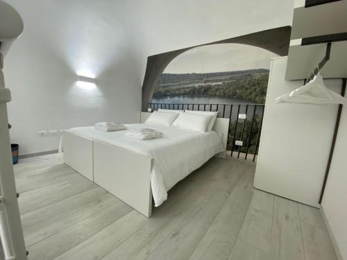 a white bedroom with a bed and a large window at La Volta in Como