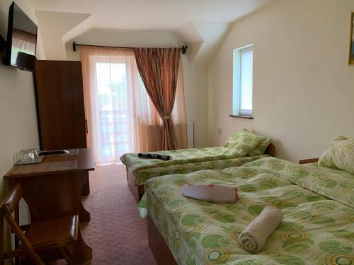 a hotel room with two beds and a desk at Casa Zmeilor in Tăşnad