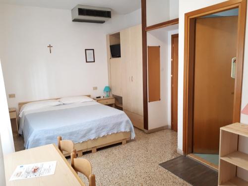 Schlafzimmer mit einem Bett, einem Tisch und einer Tür in der Unterkunft Hotel Villa Dina in Lido di Jesolo