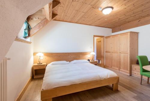 a bedroom with a large bed and a green chair at Hotel Edelhof in Tarvisio