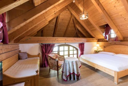 a bedroom with a bed and a table in a attic at Hotel Edelhof in Tarvisio