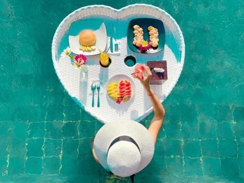 een persoon aan een hartvormige tafel naast een zwembad bij Daghan Cottage Nusa Penida in Nusa Penida