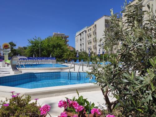 a large swimming pool in a city with pink flowers at Hotel Senior in Cattolica