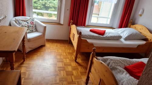 a room with two beds and a chair and a table at Hotel Kartäuser Hof Mainz Bodenheim in Bodenheim