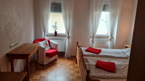 a bedroom with a bed and a chair and windows at Hotel Kartäuser Hof Mainz Bodenheim in Bodenheim