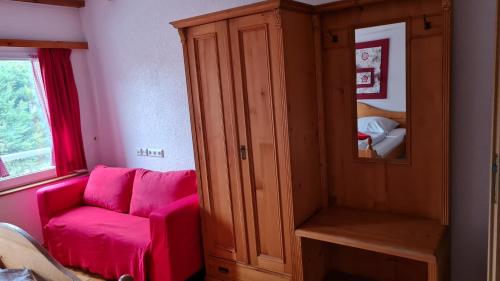 a living room with a pink couch and a cabinet at Hotel Kartäuser Hof Mainz Bodenheim in Bodenheim