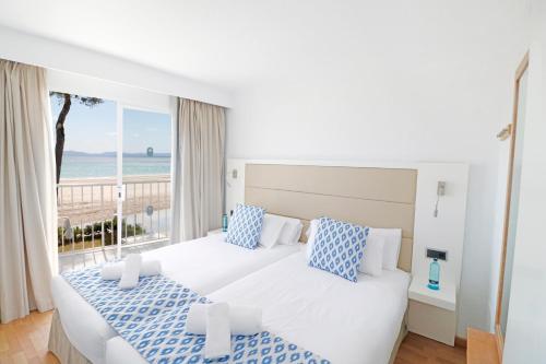 two beds in a bedroom with a view of the ocean at Bonavida Apartments in Port d'Alcudia