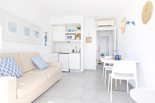een witte woonkamer met een bank en een tafel bij Bonavida Apartments in Port d'Alcudia