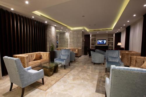 Seas Hotel Amman في عمّان: غرفة انتظار فيها كنب وكراسي وتلفزيون