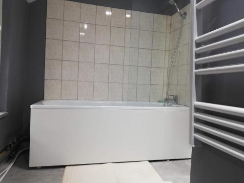 La salle de bains est pourvue d'une baignoire blanche et d'un mur carrelé. dans l'établissement Duplex Savane, Lille, à Lille