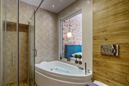 a bathroom with a tub and a glass shower at Erotokritos City Luxury Suites in Rethymno Town