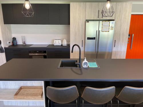 a kitchen with a sink and a counter with chairs at Ohakune Solar on Snowmass in Ohakune
