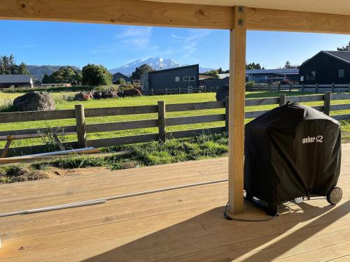 a suitcase sitting on a wooden deck with a view of a field at Ohakune Solar on Snowmass in Ohakune