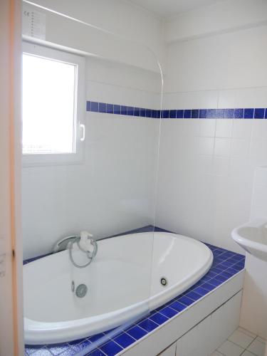 eine weiße Badewanne im Bad mit Fenster in der Unterkunft Une Vue Exceptionnelle in La Trinité-sur-Mer