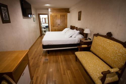 a hotel room with a bed and a couch at Hospedium Hotel Rural Abadía de Yuste in Cuacos de Yuste