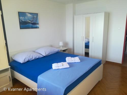 a bedroom with a blue bed with two towels on it at Kvarner Apartments - Mošćenička Draga in Mošćenička Draga