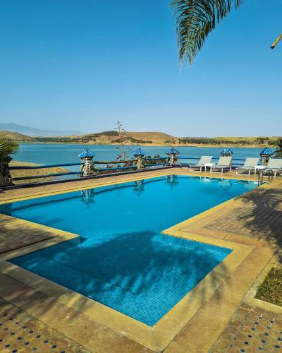 a large swimming pool next to a body of water at Rive Du Lac in Lalla Takerkoust