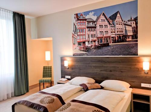 two beds in a hotel room with a picture on the wall at Mainzer Hof in Mainz