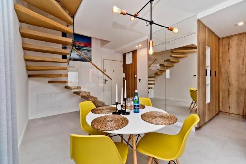 亞斯塔爾尼亞的住宿－BlueApart Apartland Residence，一间设有白色桌子和黄色椅子的用餐室