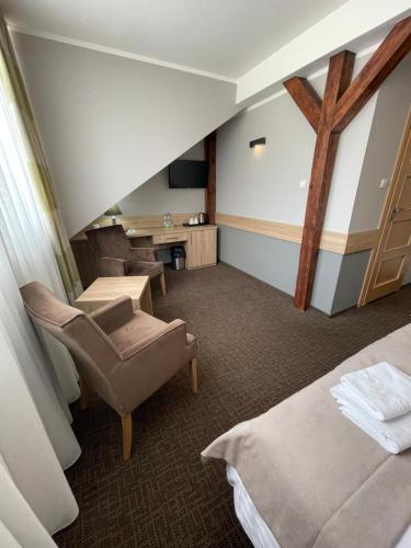 a hotel room with a bed and a desk and chairs at Hotel Mużakowski in Łęknica